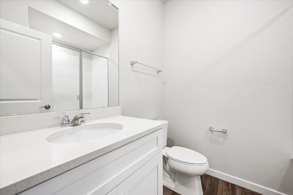 A bathroom with a sink toilet and mirror.