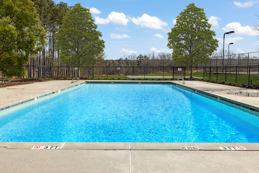 A swimming pool with trees and a fence around it.