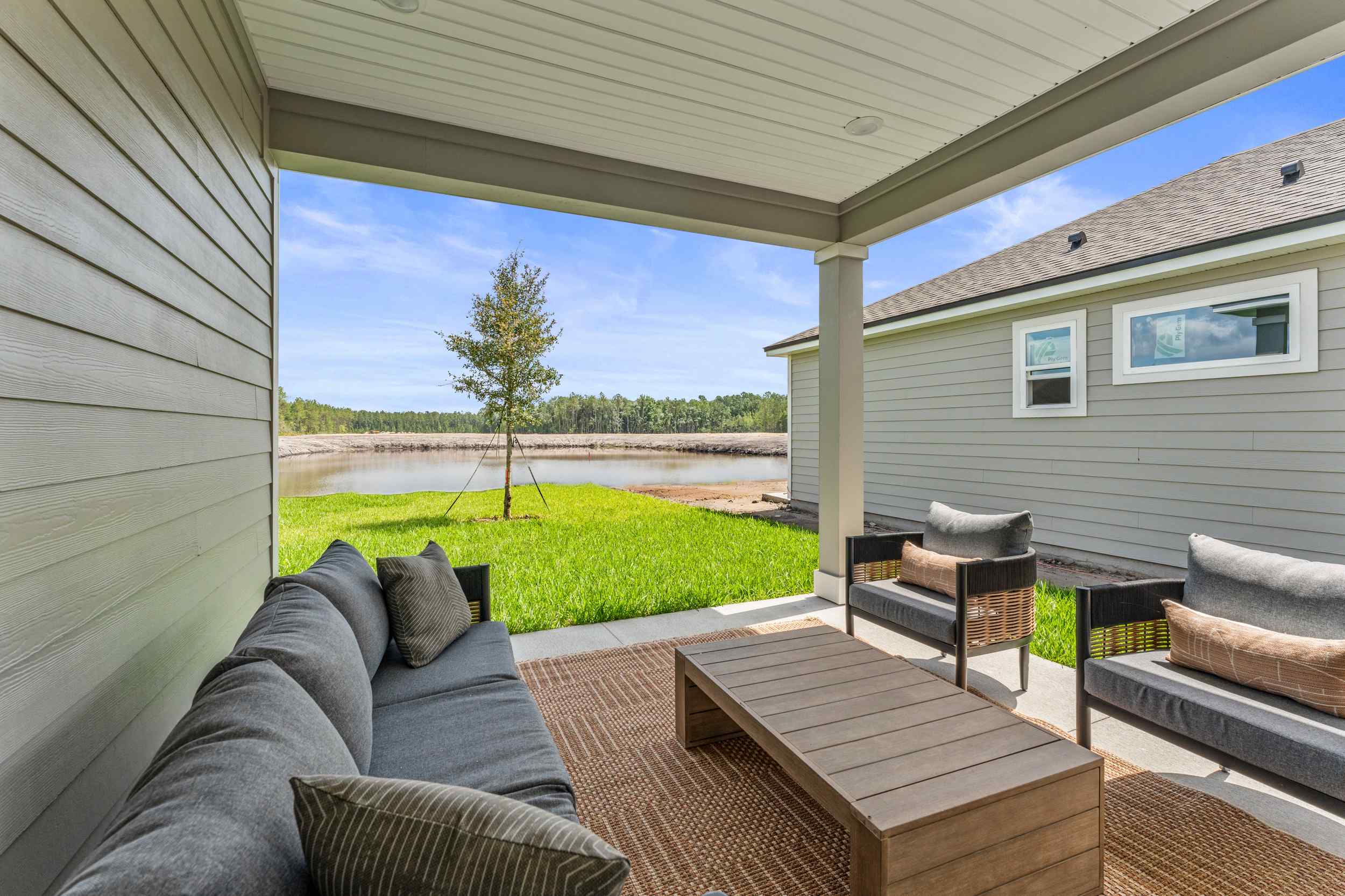 Silverbell II Model Home Covered Patio with Couch and Chairs Overlooking Water at Camden Woods in Kingsland, GA