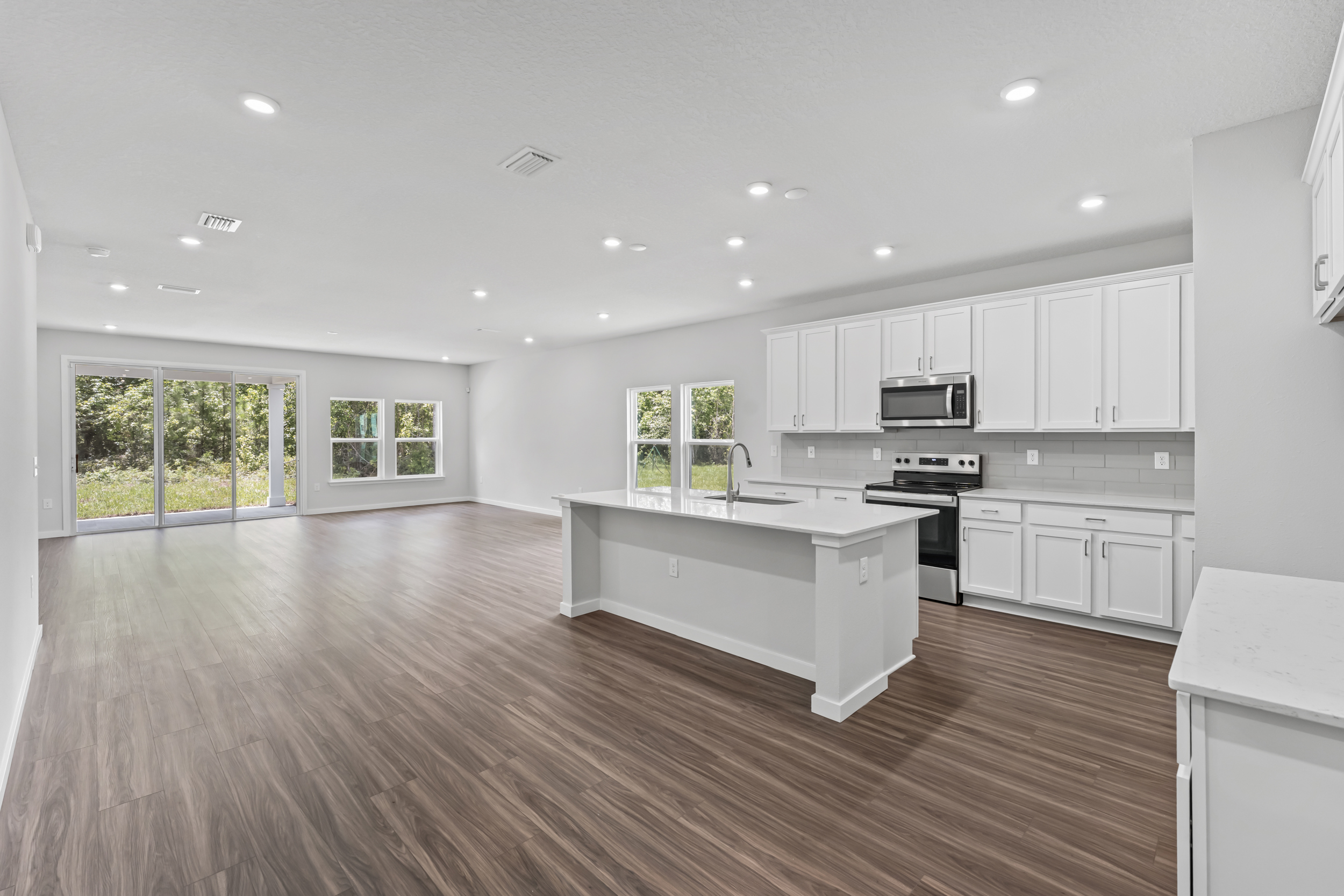 Dogwood Floor Plan Great Room with Dark Flooring and White Kitchen Cabinets at NorthShore in Kingsland