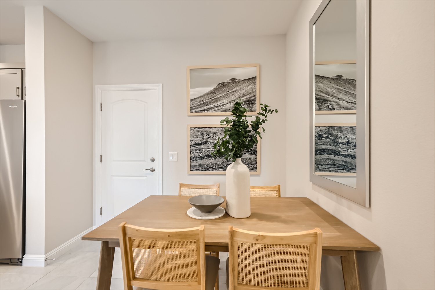 A dining room table with chairs and a vase with a plant on it.
