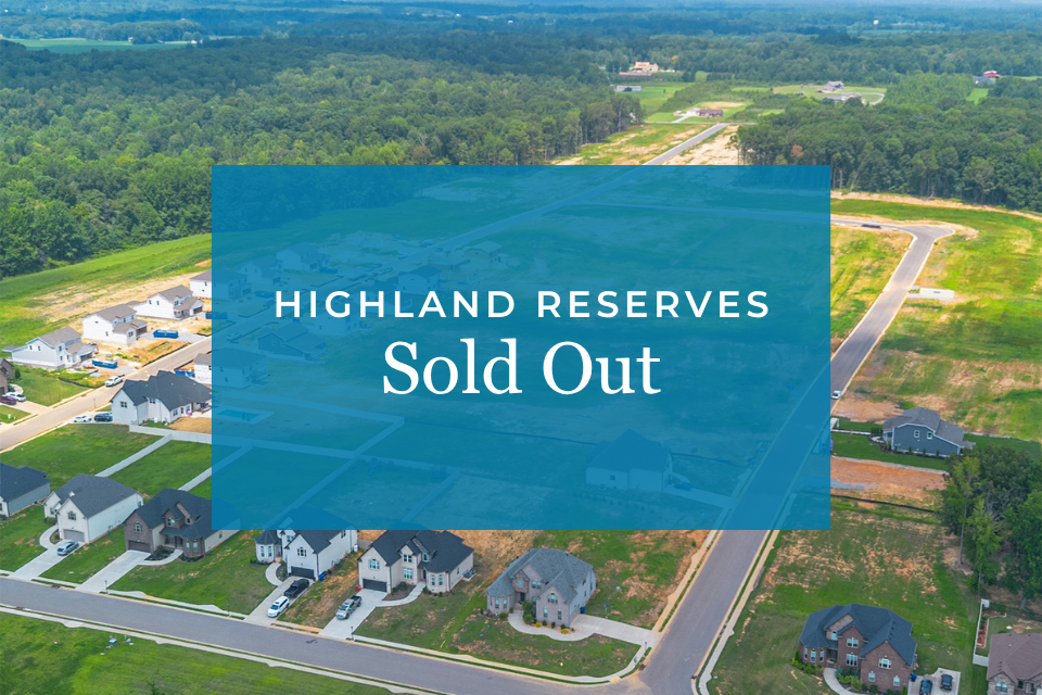 A large green field with houses and trees.