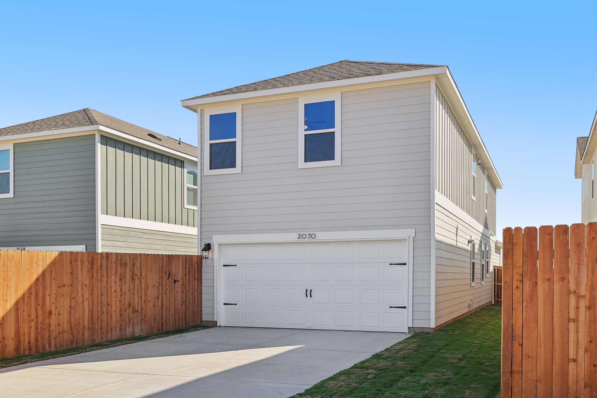 A white garage next to a wooden fence.