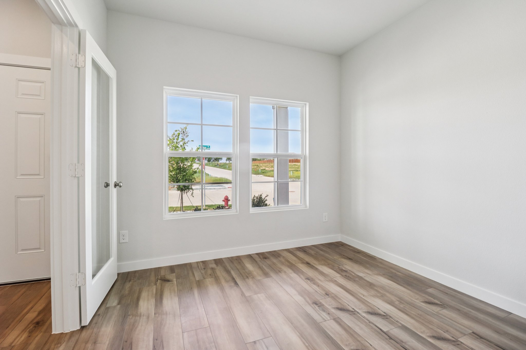 A room with a window and a wood floor.