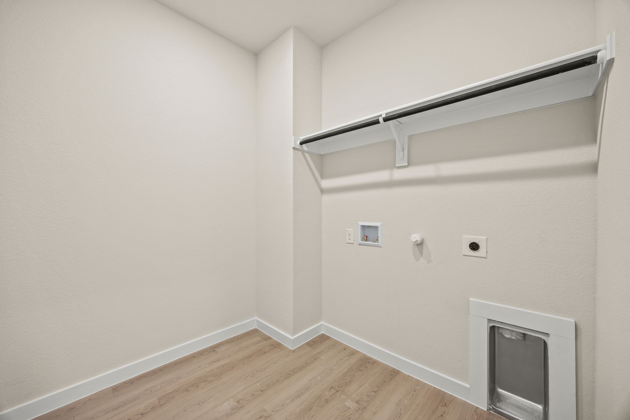 A room with a wood floor and a white wall with a tv.