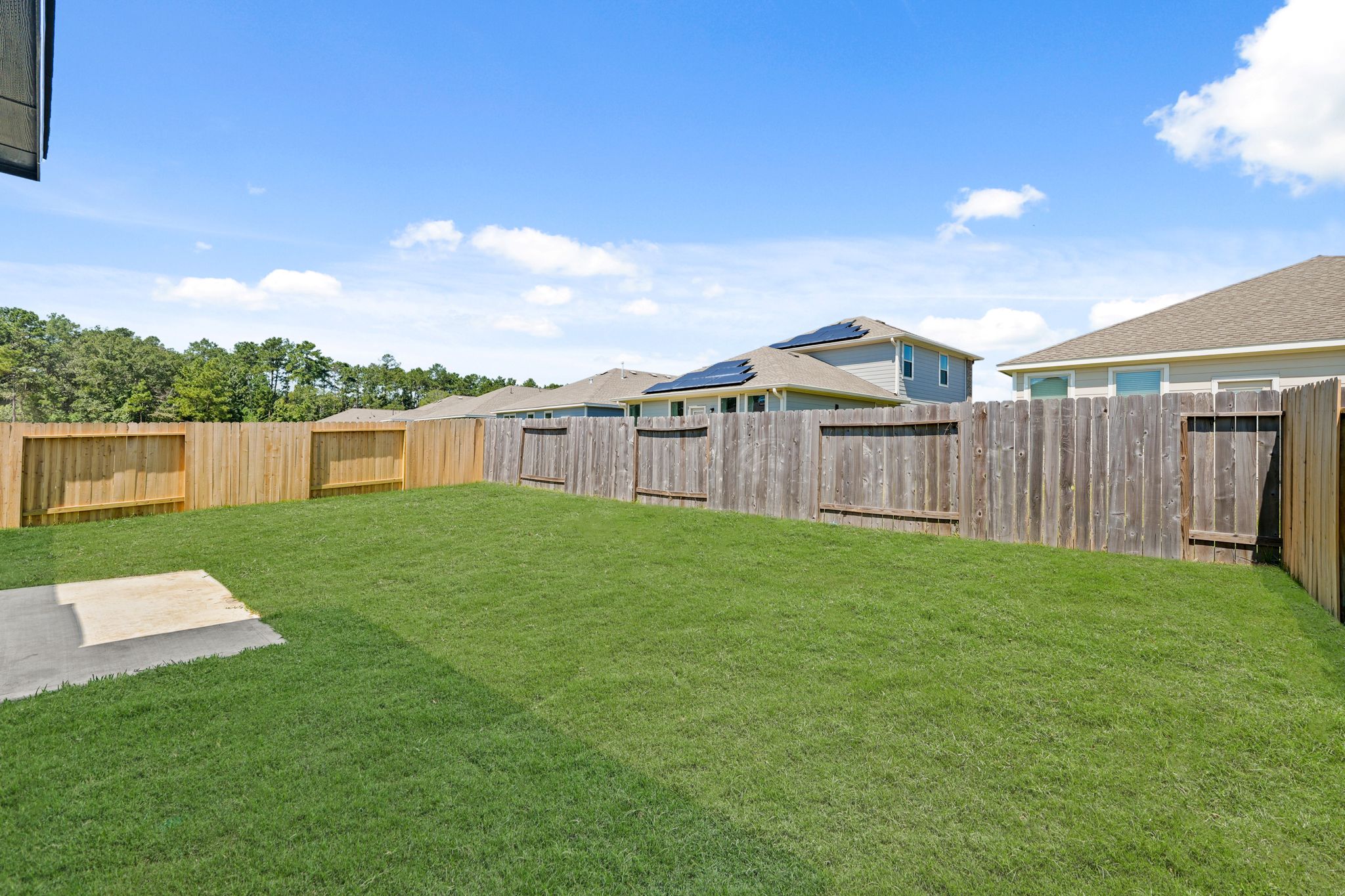 A fenced in yard with a house in the background.