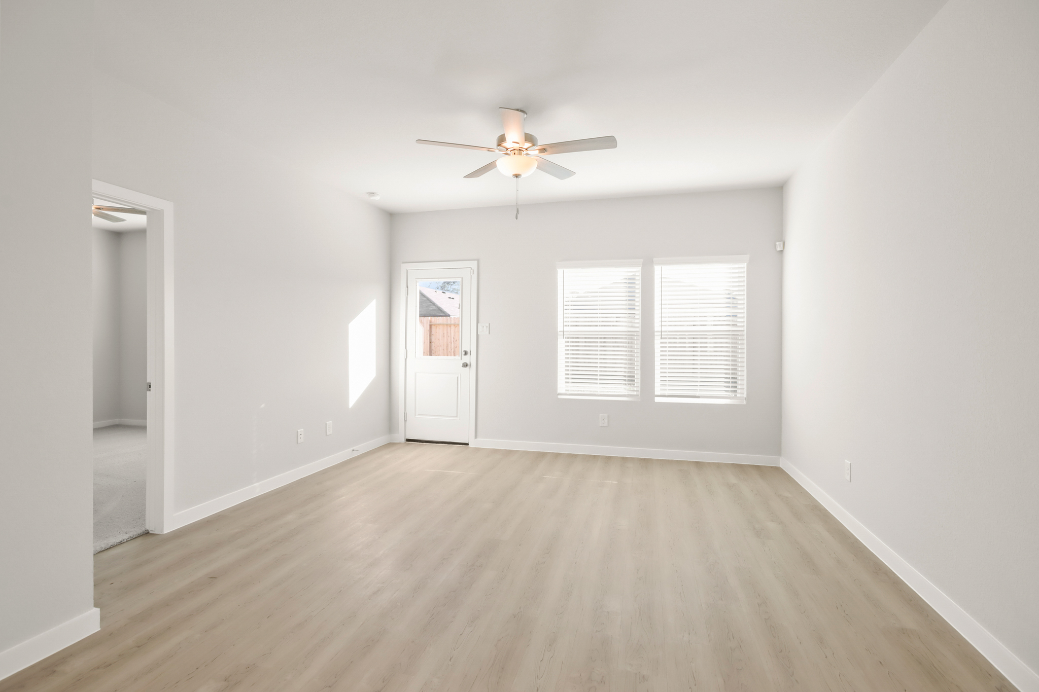 A room with a wood floor and a ceiling fan.