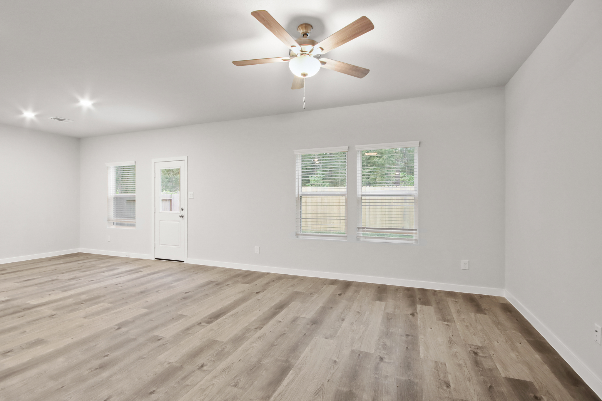 A room with a ceiling fan and a wood floor.