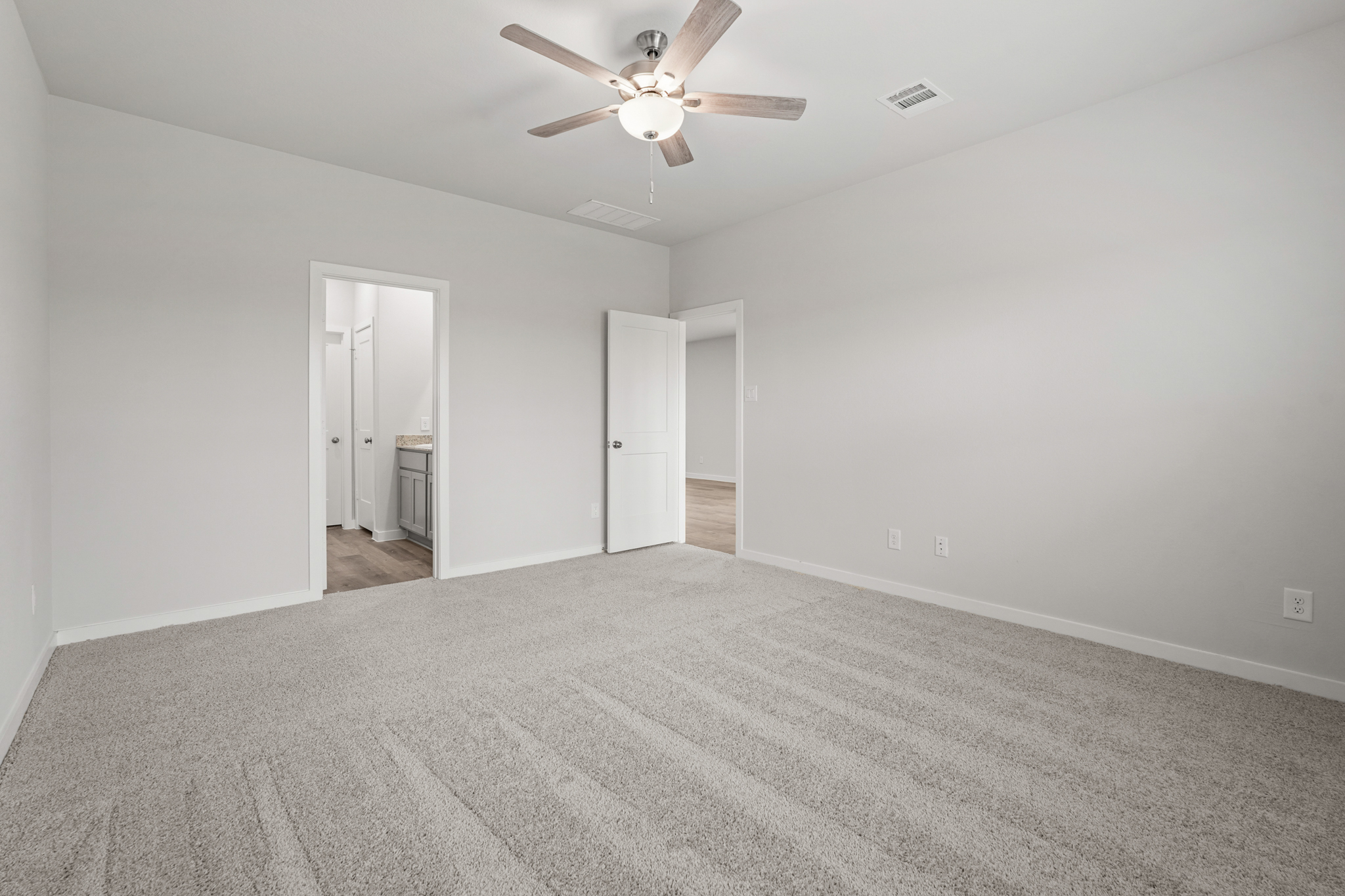 A room with a ceiling fan and a carpet.