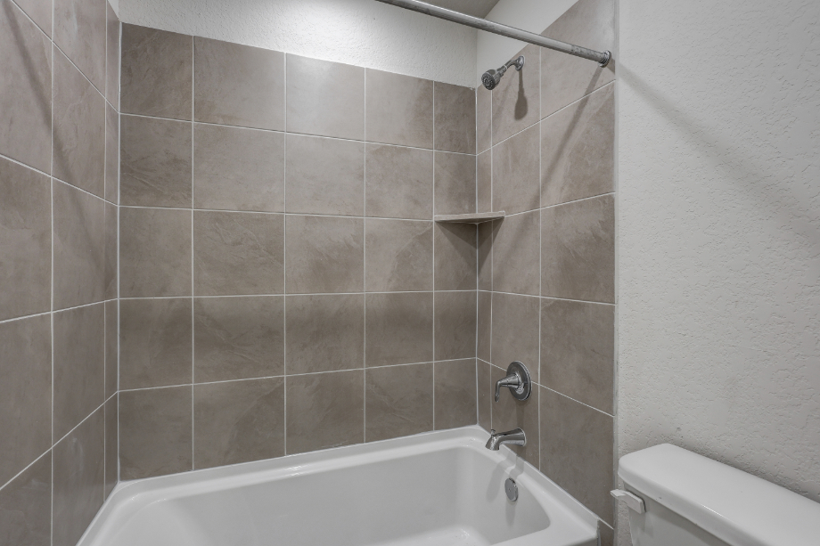 A bathroom with a bathtub and tile walls.