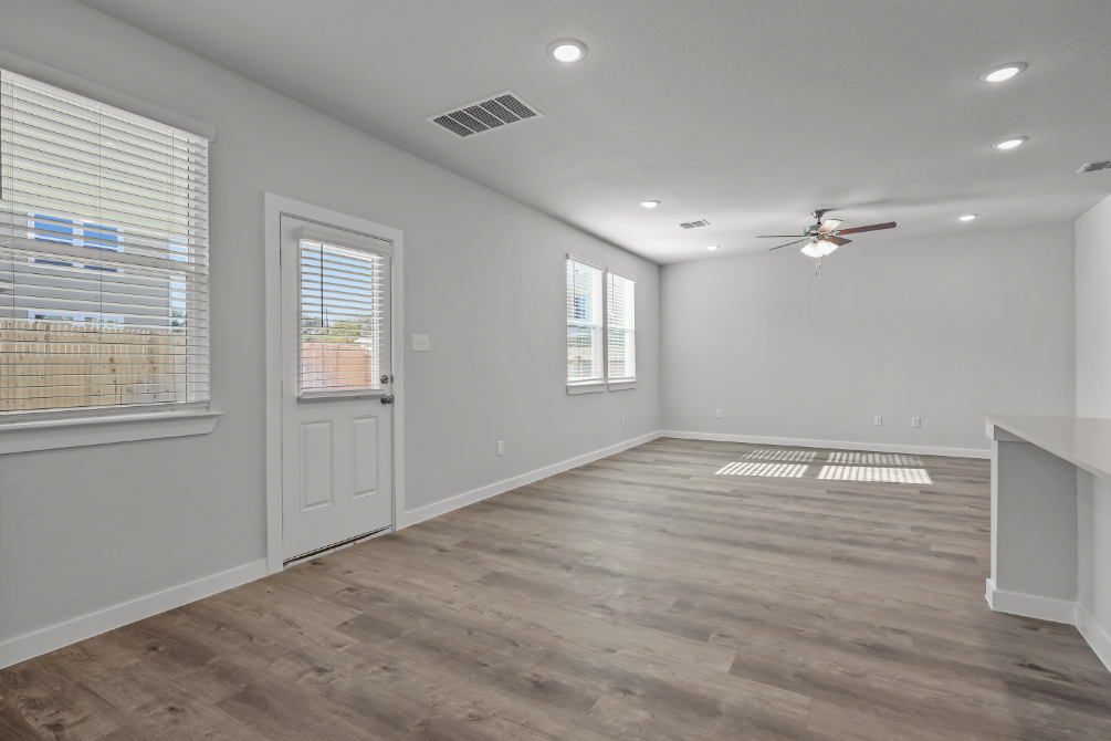 A room with a wood floor and a wood floor with a fan.