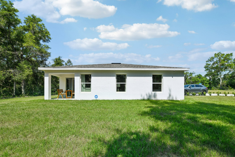 A white house with a car parked in the yard.