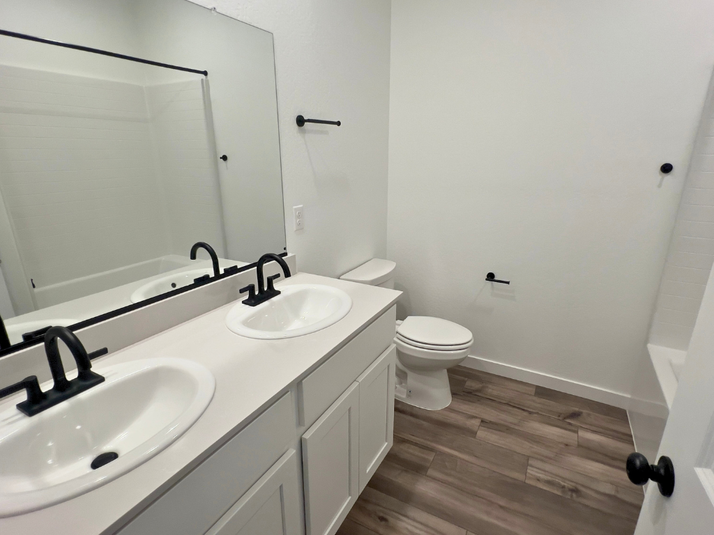 A bathroom with a sink toilet and a mirror.